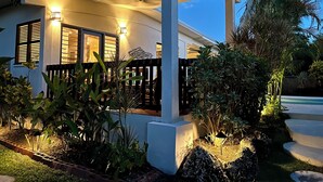 Een huis met een overdekte veranda, een plafondventilator en een goed verlichte buitenkant.