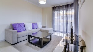Een moderne woonkamer met een bank, salontafel en een flatscreen televisie.