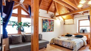 A cozy bedroom with a bed, a sofa, and a large window. - B and B Saules Namai (Vilnius)