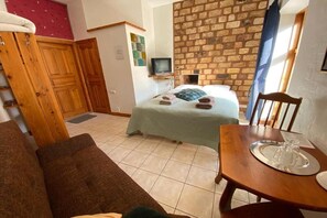 Une pièce confortable avec un lit, une armoire en bois, un téléviseur et une table à manger avec un plateau.