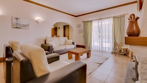 A living room with a sofa, a coffee table, and a dining area with chairs.