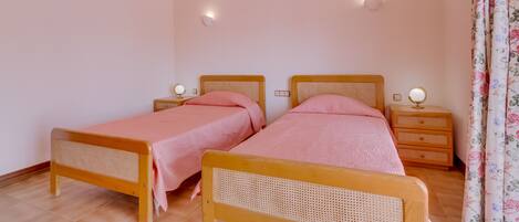 A bedroom with two wooden beds, each with a headboard and footboard, and a bedside table with a mirror.