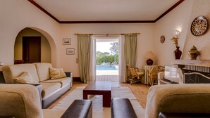 A living room with a sofa, armchairs, a coffee table, and a view of an outdoor swimming pool.