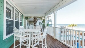 A covered porch with a wooden table and white chairs, overlooking a pool and ocean view. - Oceanfront 5 BR Beach House with a Private Pool! Tranquility (Surfside Beach)