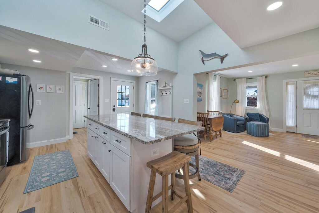 A spacious kitchen with a central island, wooden flooring, and a skylight.