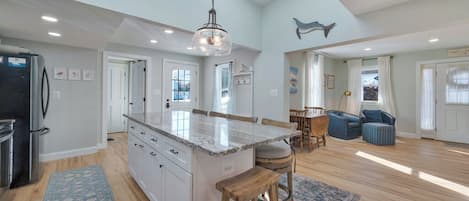 A spacious kitchen with a central island, wooden flooring, and a skylight.
