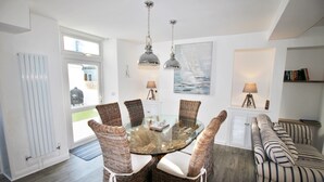 A dining area with a glass table surrounded by wicker chairs, a sofa, and pendant lighting. - Fantastic location in the harbour bowl (Brixham)