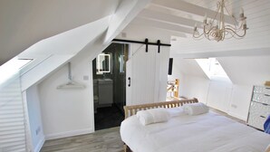 A bedroom with a sloped ceiling, a wooden bed, a chandelier, and a view through a skylight. - Fantastic location in the harbour bowl (Brixham)