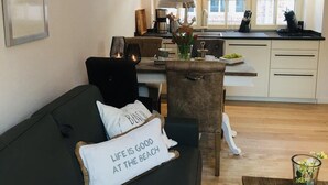 Ein modernes Wohnzimmer mit einem dunkelgrünen Sofa, einem Couchtisch und Blick auf eine Küche und Essbereich.