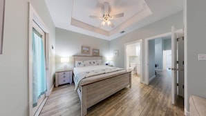 Ein Schlafzimmer mit Bett, Nachttischen, Deckenventilator und Blick ins Bad.