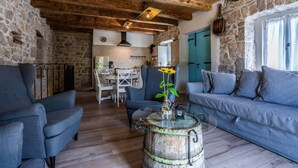 A rustic interior with stone walls, wooden beams, a dining area, and a sofa. - Stone house Katarina with swimming pool, only 50 meters from the Sea (Klimno (Krk))