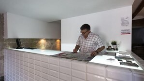 A man at a reception desk with a map, a computer, and a small plant. - Dingdong Nuns (Valencia)