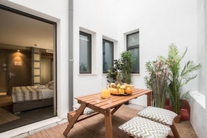 A room with a bed, a wooden table with fruit and a drink, and potted plants. - Dingdong Nuns (Valencia)