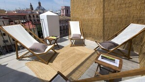 A rooftop terrace with two lounge chairs, a small table, and a woven mat. - Dingdong Nuns (Valencia)