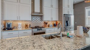 A modern kitchen with white cabinets, a stainless steel refrigerator, and a granite countertop.