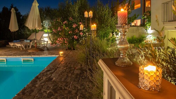 A poolside area with a stone deck, lounge chairs, and a candle-lit table. - Villa Dada with pool, Seaview and playroom (Linardići (Krk))
