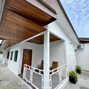 A covered outdoor area with a wooden ceiling, white walls, and a door. There are two potted plants and a white railing. - Airis Sanctuary Resort (Langkawi)