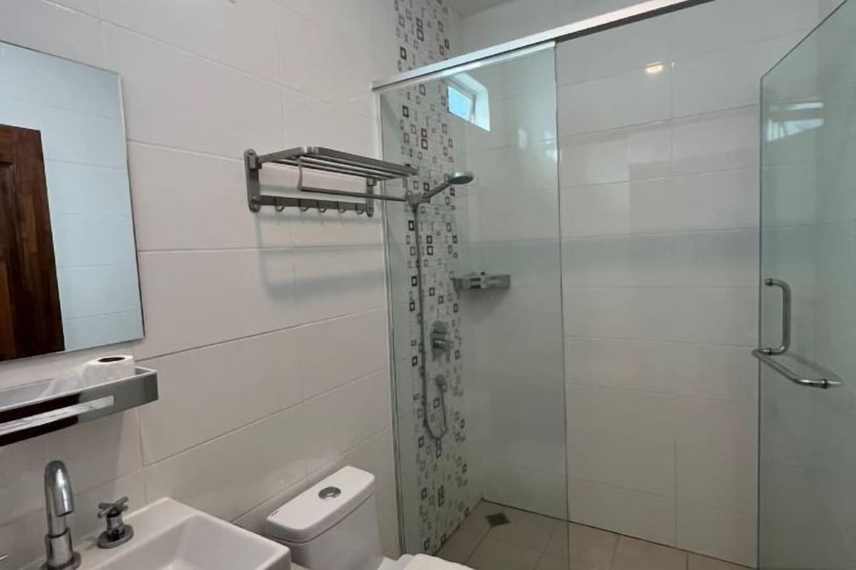 A modern bathroom with a glass shower enclosure, a toilet, a sink with a faucet, and a mirror above the sink.