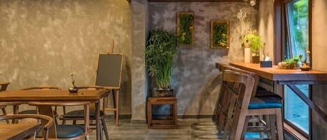 Un comedor moderno con una larga mesa de madera y sillas, una pequeña planta en maceta y una barra con taburetes.
