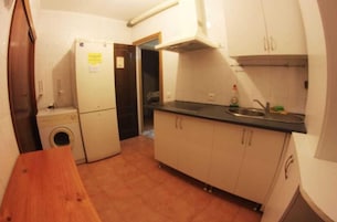A compact kitchen with a washing machine, a sink, and cabinets.