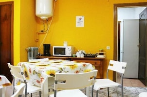 A dining area with a table set for four, a microwave, and a small cabinet.