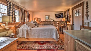 Ein gemütliches Schlafzimmer mit einem großen Bett, einem Holz-Kopfteil, einem Nachttisch mit Lampe, einem Teppich und einem Kamin.