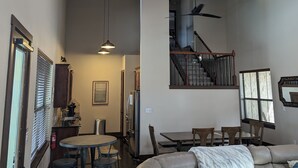 A spacious living area with a high ceiling, a dining table, and a leather sofa.
