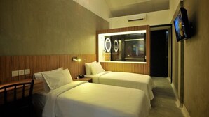 A hotel room with two beds, a wooden headboard, a bedside table, a mirror, and a TV mounted on the wall. - The Yard Boutique Hotel (Kuala Lumpur)