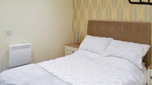 Une chambre à coucher avec un lit, une table de chevet, un radiateur et un papier peint à motifs.