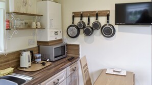 Une cuisine compacte équipée d’un four à micro-ondes, d’une bouilloire et d’une petite table avec un carnet.