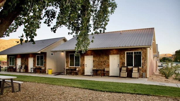 A row of single-story buildings with stone facades and metal roofs, each with a door and windows, and outdoor seating areas. - Bunkhouse 5A Under Cottonwood Trees (La Verkin)