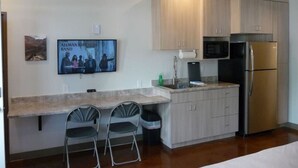 Una cocina compacta con microondas, refrigerador y un pequeño comedor con dos sillas.