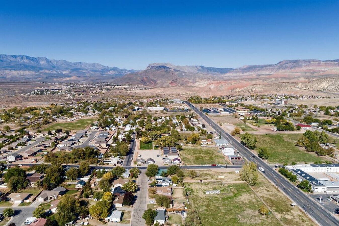 An aerial view of a residential area with houses, roads, and mountains in the background.