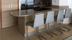 Una cocina moderna con encimera de granito, electrodomésticos de acero inoxidable y taburetes de bar.