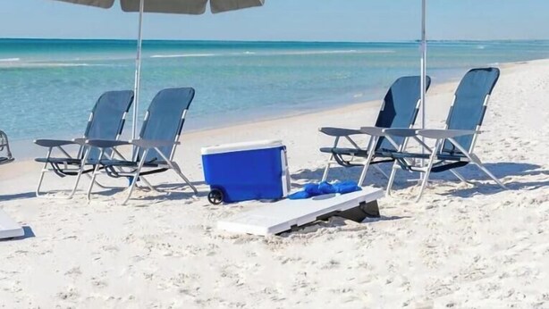 Una playa con dos sombrillas y sillas de playa.