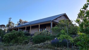 A house with a sloped roof, brick exterior, and a covered porch. - Dog Friendly Snowy Mountains Cottage on Acres (Berridale)