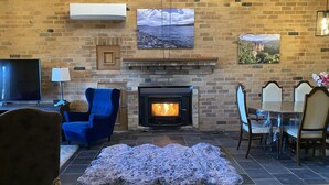 A living room with a fireplace, a television, and a dining area with chairs and a table. - Dog Friendly Snowy Mountains Cottage on Acres (Berridale)
