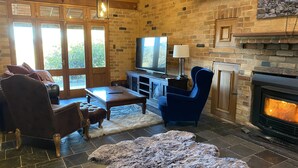 A cozy living room with a fireplace, a television, and comfortable seating. - Dog Friendly Snowy Mountains Cottage on Acres (Berridale)