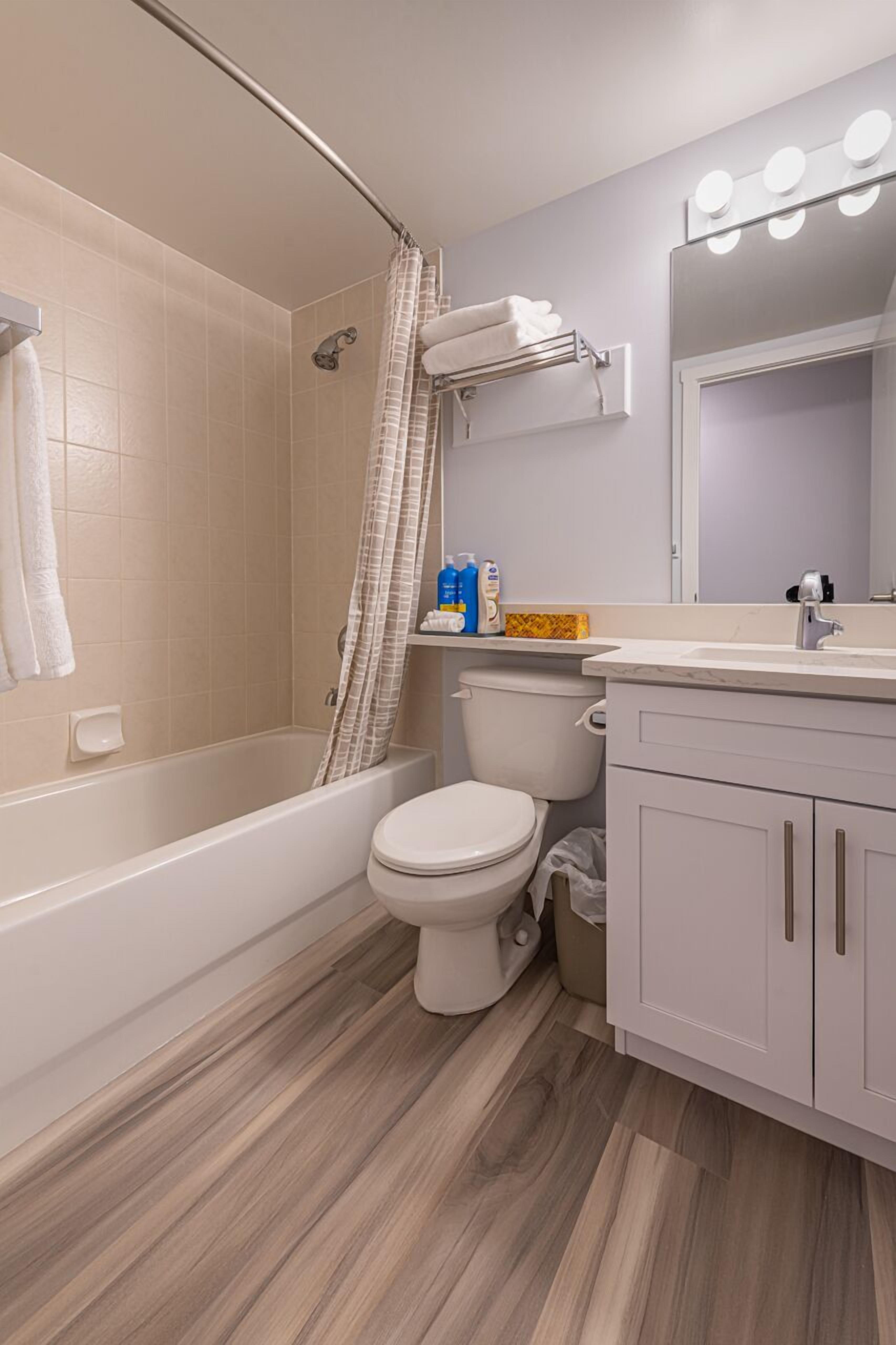 A modern bathroom with a bathtub, toilet, and vanity.