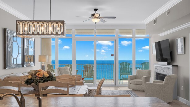 A spacious living room with a large window overlooking the ocean, a ceiling fan, and a dining area with a marble countertop. -  Check out specials for August/Fall stays  ! Spectacular views in newer complex! (Orange Beach)