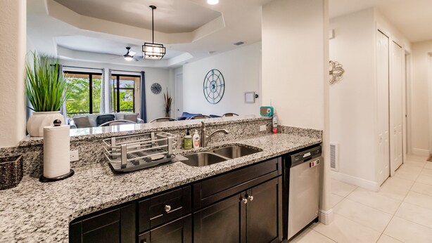 A kitchen with granite countertops, stainless steel appliances, and a view of the living area through large windows.