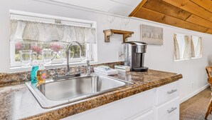 Una cocina con encimera de granito, pileta de acero inoxidable y cafetera.