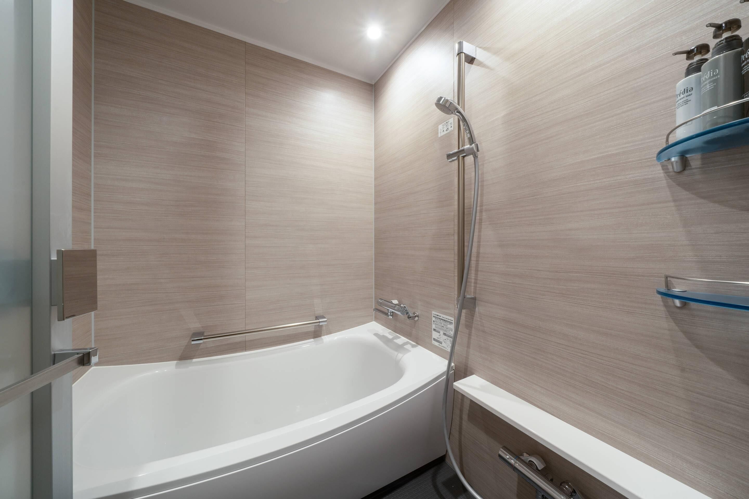 A modern bathroom with a freestanding bathtub, a showerhead, and a shelf with toiletries.