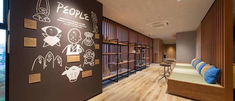 Um interior moderno com piso de madeira, parede com diversos ícones e texto, e um espaço de estar com almofadas.