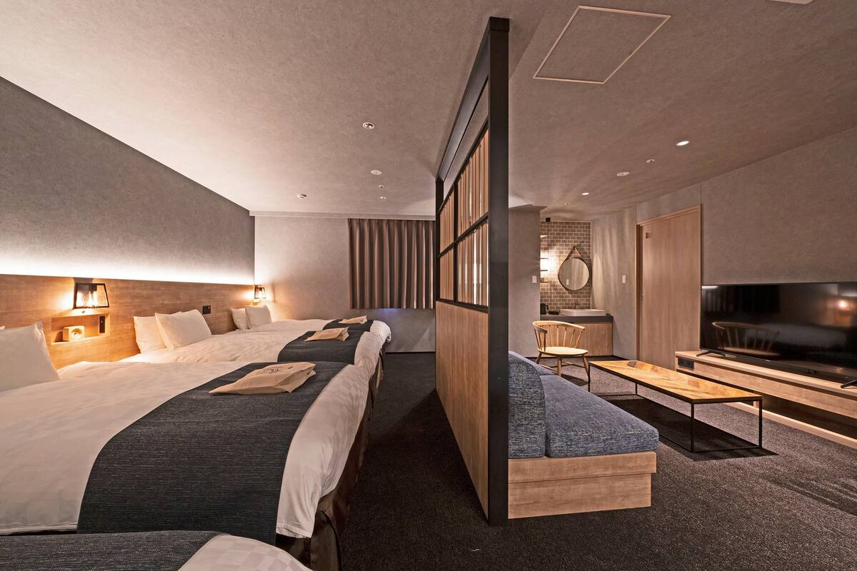 A modern hotel room with a large bed, a sofa, a TV, and a desk.