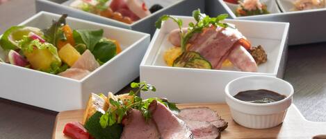Una variedad de platos, incluyendo una ensalada, carne en rodajas y un pequeño bol de salsa, dispuestos sobre una tabla de madera.