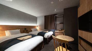 Habitación de hotel con dos camas, una mesita pequeña, una silla, un televisor y un armario de madera.