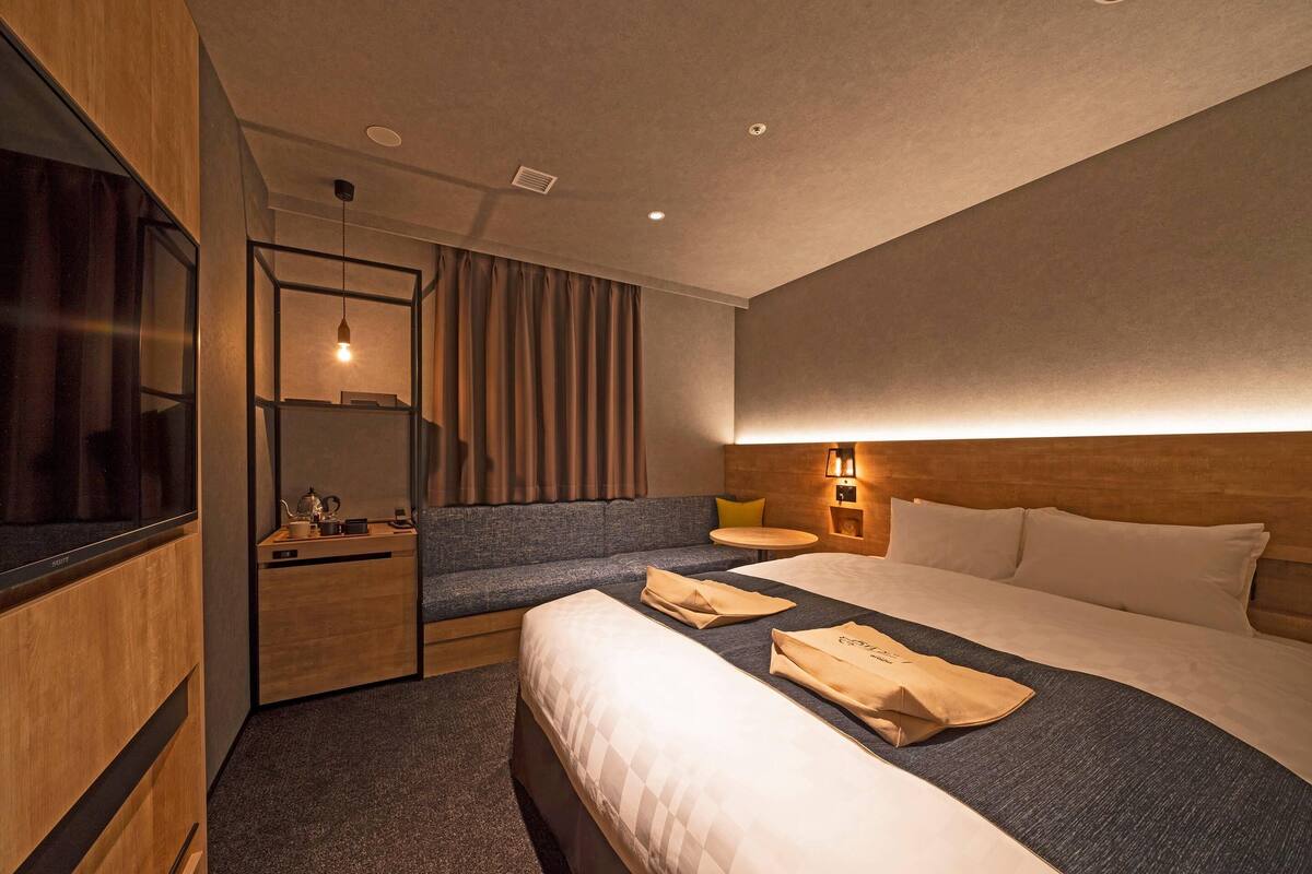 A hotel room with a bed, a sofa, a desk, and a TV.