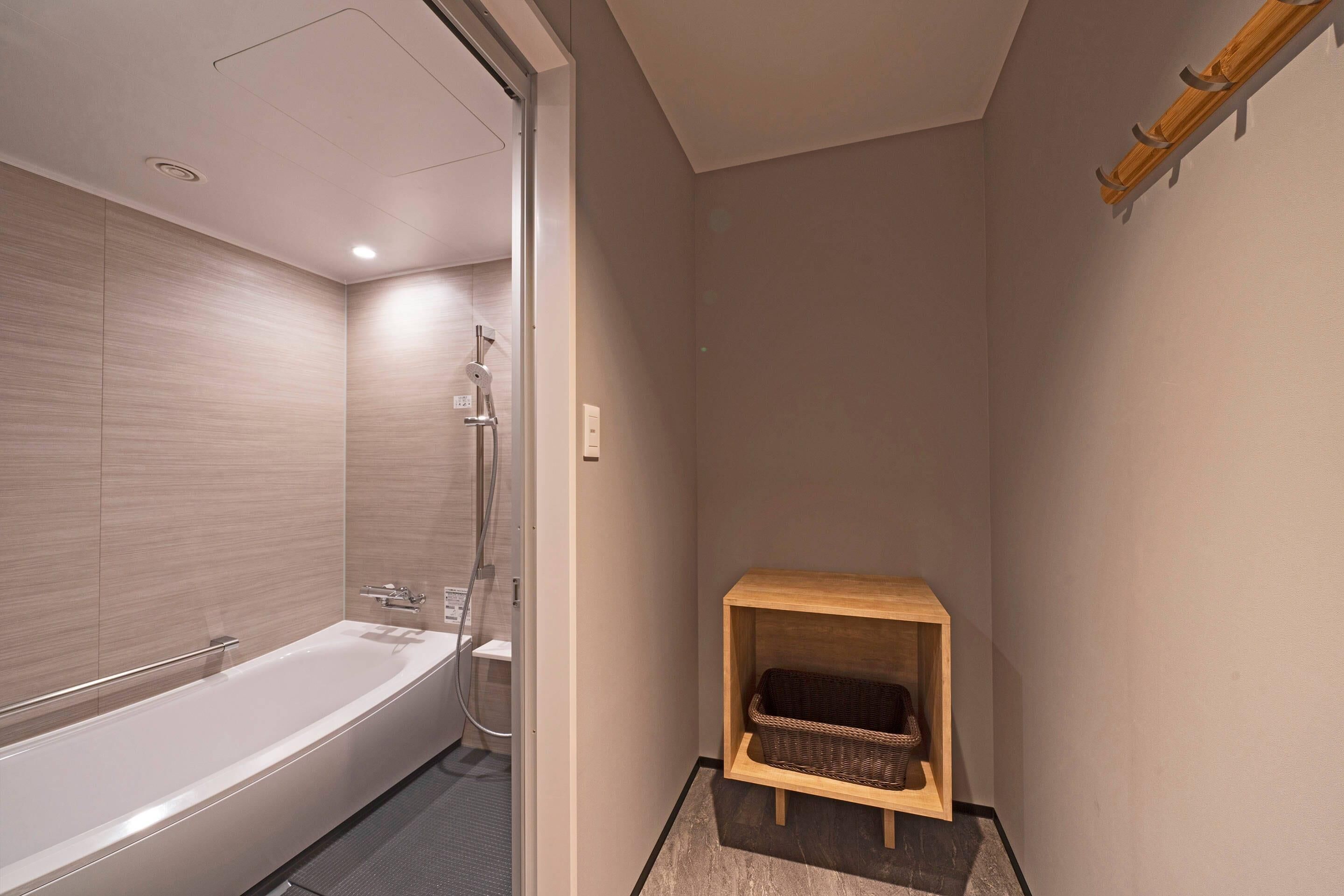 A modern bathroom with a bathtub, shower, and a wooden shelf with a basket.
