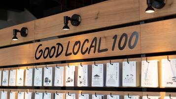 A wooden sign with 'GOOD LOCAL 100' and multiple hanging cards with illustrations.